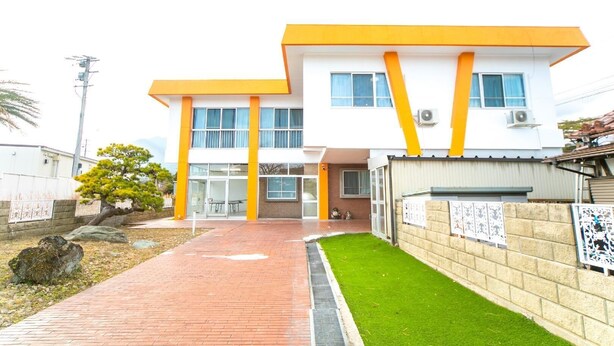Un bâtiment moderne à deux étages, avec un chemin en briques menant à l’entrée.