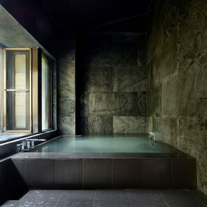 Um spa moderno com parede de pedra, uma janela grande e uma banheira.