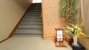 A staircase with a bamboo mat, a lantern, and a vase with flowers. - Dai Onsen Ryokan Kanegaya (Hanamaki)