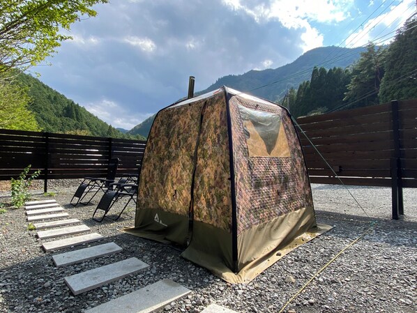 A tent with camouflage fabric, set up on a gravel surface with stepping stones leading to it. - Tanba Hoshizora Glamping Shigura Resort (Tamba)