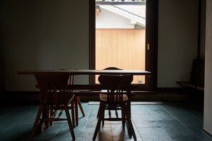 A room with a wooden table and two chairs, a sliding door leading to an outdoor area, and a tiled floor. - Touto Nihon Kyodo Gangukan Kura no Yado (Kurashiki)