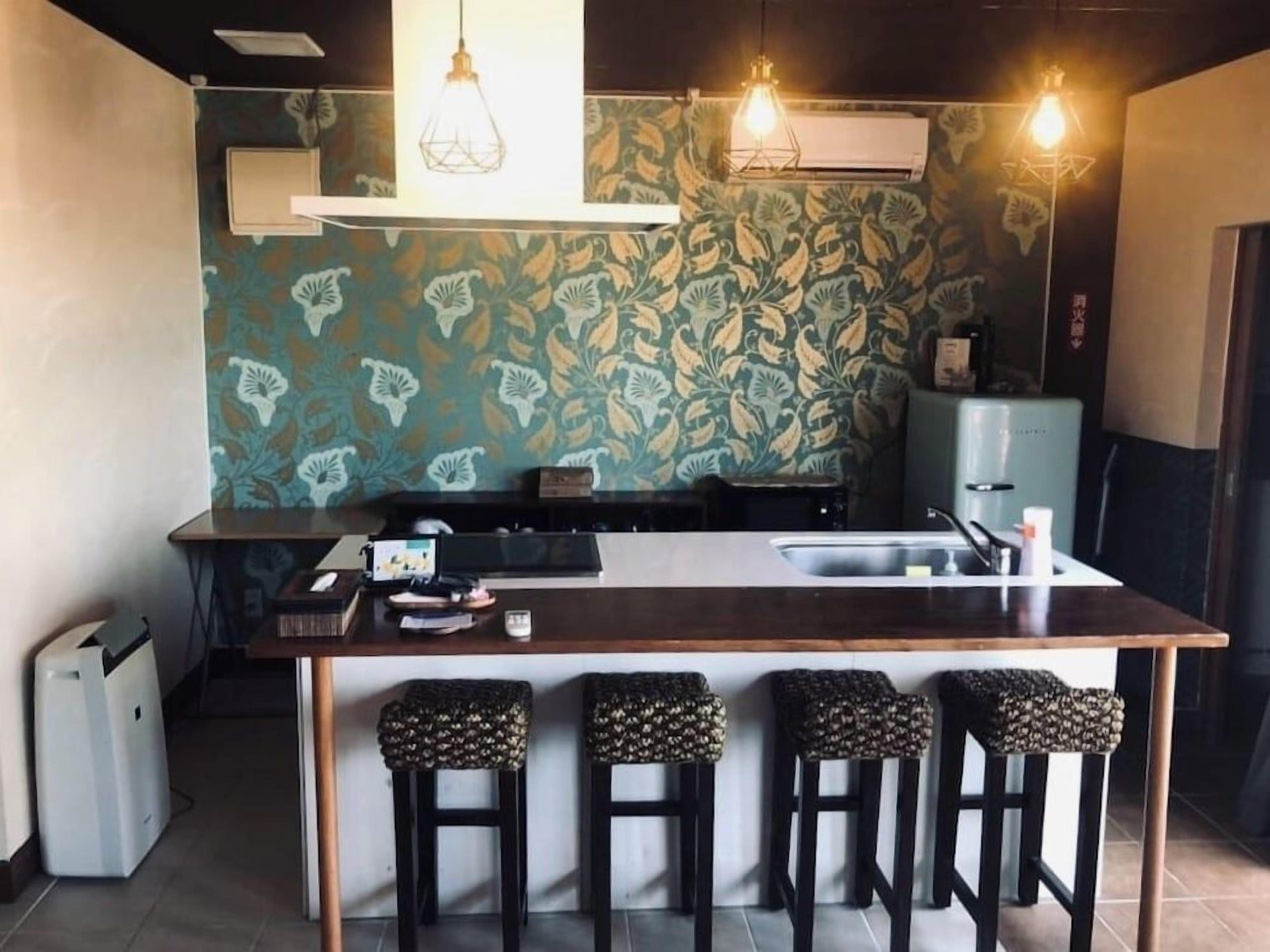 A kitchen with a central island, bar stools, and pendant lighting.