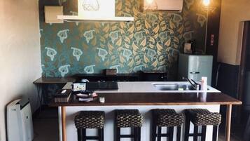 A kitchen with a central island, bar stools, and pendant lighting.