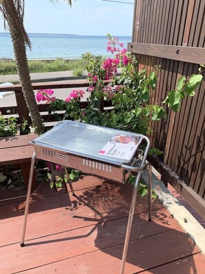 Una parrilla con una carta de menú, ubicada en una terraza de madera con vista al mar.