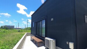 Un edificio moderno con fachada oscura, amplios ventanales y un pequeño espacio exterior con banco.
