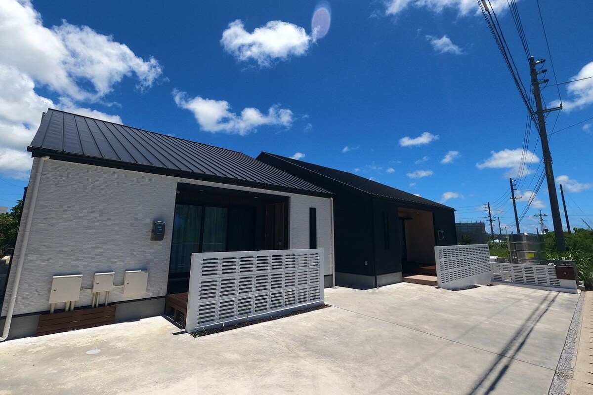 A modern building with a flat roof, large windows, and a concrete patio area.