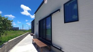 Un edificio moderno con amplios ventanales, un camino de hormigón y un banco de madera.