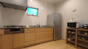 Una cocina compacta con armarios de madera, electrodomésticos de acero inoxidable, microondas integrado y ventana sobre el lavamanos.