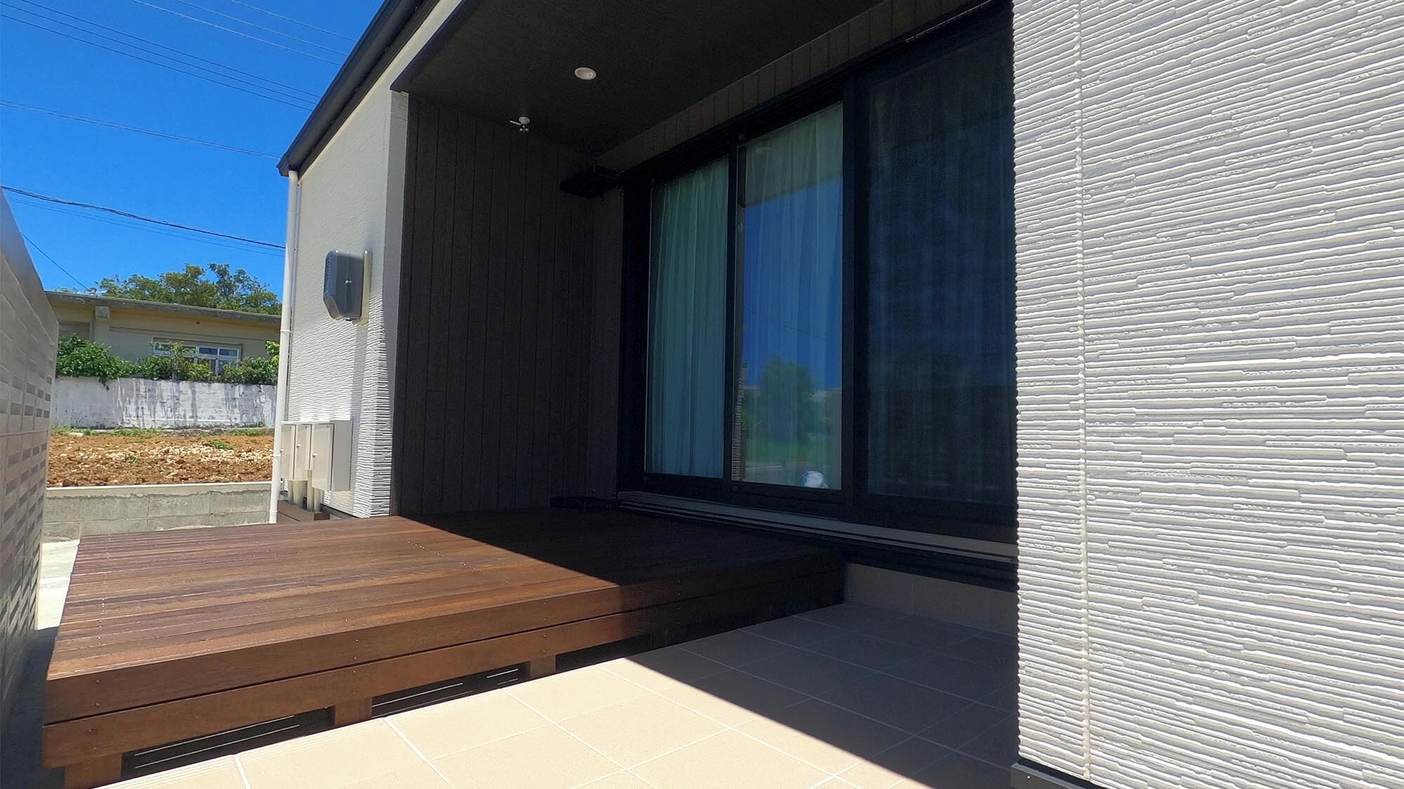 Un edificio moderno con terraza de madera, ventanas amplias y suelo de baldosas.
