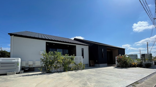 A modern two-story house with a flat roof, large windows, and a concrete driveway. - Yuni no Hama Panari (Miyakojima)