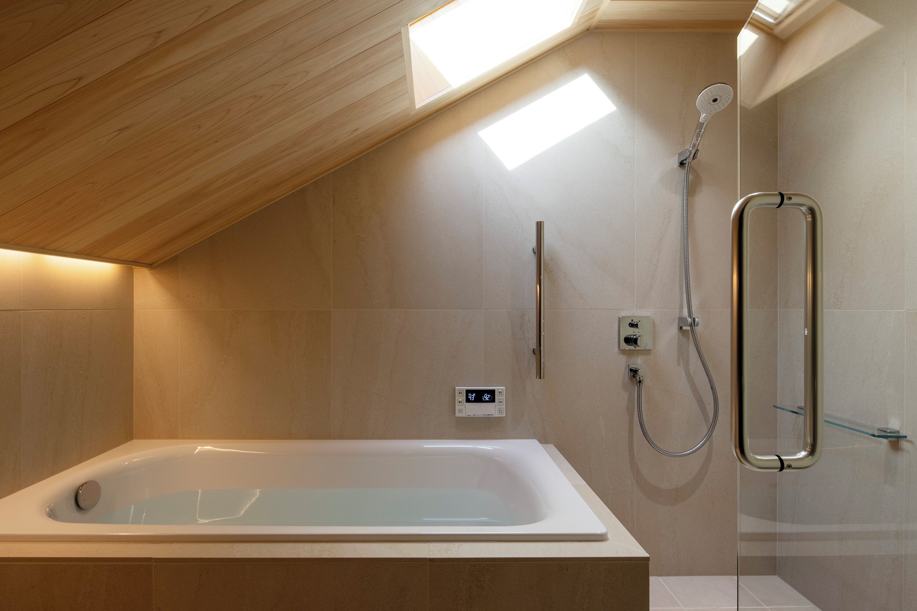 A modern bathroom with a freestanding bathtub, a glass-enclosed shower, and a skylight.