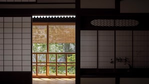 Een traditionele Japanse kamer met tatami vloeren, shoji schermen en uitzicht op groen buiten.