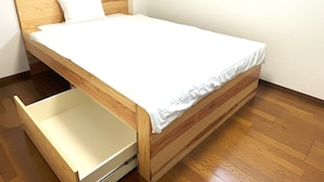 Ein Einzelbett mit Holzrahmen und einer weißen Matratze, Holzboden und weiße Wand.