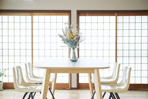 A dining table with a vase of flowers in the center, surrounded by chairs.