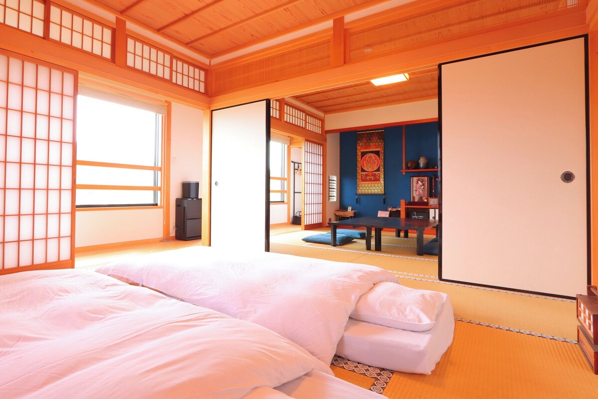 A traditional Japanese room with tatami flooring, a futon bed, sliding doors, and a shoji screen.