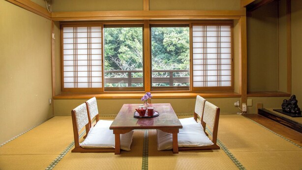A traditional Japanese room with tatami flooring, a low wooden table with cushions, and a view through shoji screens. - Kokubunya (Iwade)