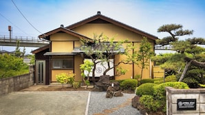 A traditional Japanese-style building with a tiled roof, a stone pathway leading to the entrance, and a well-maintained garden with rocks and trees. - Temple Hotel Hogenji (Minami-Alps)