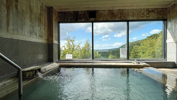 Un bain dans une source thermale, avec vue sur une colline boisée.