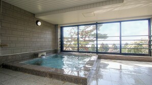 Une grande piscine intérieure avec une vue sur les arbres, visible à travers une grande fenêtre.