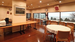Une salle de conférence avec de longues tables, des chaises, une horloge et un tableau accroché au mur.
