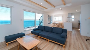 Un salon moderne avec un canapé, une table basse et une vue sur la mer.