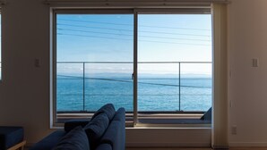 Une pièce dotée d’une grande fenêtre donnant sur la mer, d’un canapé et d’une petite table.