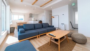 Un salon moderne avec un canapé bleu, une table basse en bois et une grande fenêtre.