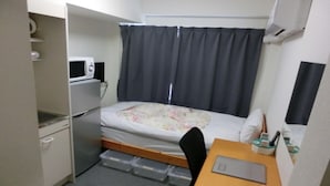 A compact hotel room with a bed, a desk, a microwave, and a small storage unit. - Hotel I-room Rikuzentakata (Rikuzentakata)