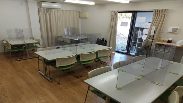 A conference room with tables and chairs, air conditioning units, and a view of the outdoors through a glass door. - Hotel I-room Rikuzentakata (Rikuzentakata)