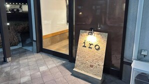 A modern building entrance with a glass door, a wooden floor, and a sign with the word "iro" illuminated. - Hotel I-room Rikuzentakata (Rikuzentakata)