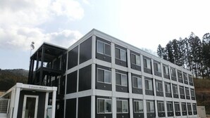 A modern multi-story building with a symmetrical facade, large windows, and a small entrance area with steps. - Hotel I-room Rikuzentakata (Rikuzentakata)