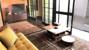 A modern living room with a sofa, a small table, and a TV. - Rakuan (Hakodate)