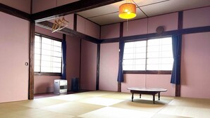 A tatami mat room with a traditional Japanese-style table, a heater, and a hanging lamp. - Rakuan (Hakodate)