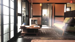 A room with a large window, a heater, a clock, and a sofa. - Rakuan (Hakodate)