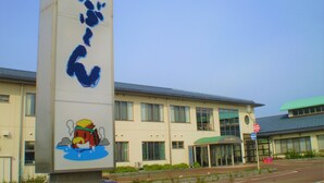 Un edificio con un letrero grande que muestra un personaje de caricatura y texto en japonés.