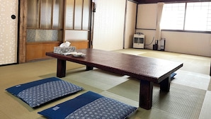 A traditional tatami room with a wooden table, tatami mats, a heater, and a sliding door.