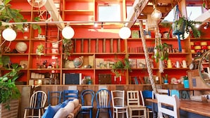 A cozy room with a wooden floor, a bed with blue pillows, and a variety of chairs and tables. - L'art de Vie (Matsuyama)