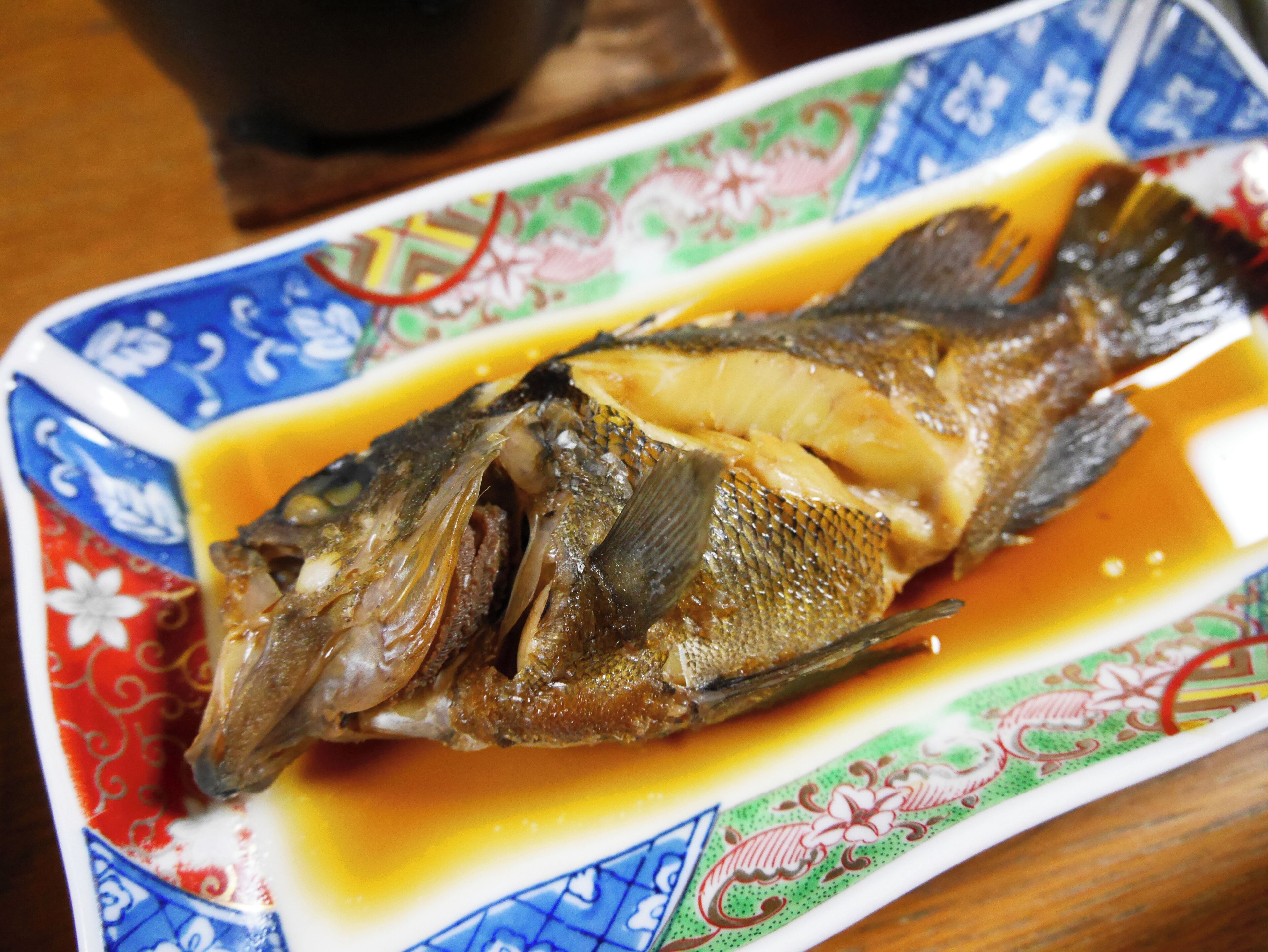 Ein ganzer Fisch auf einer verzierten Platte mit Soße.