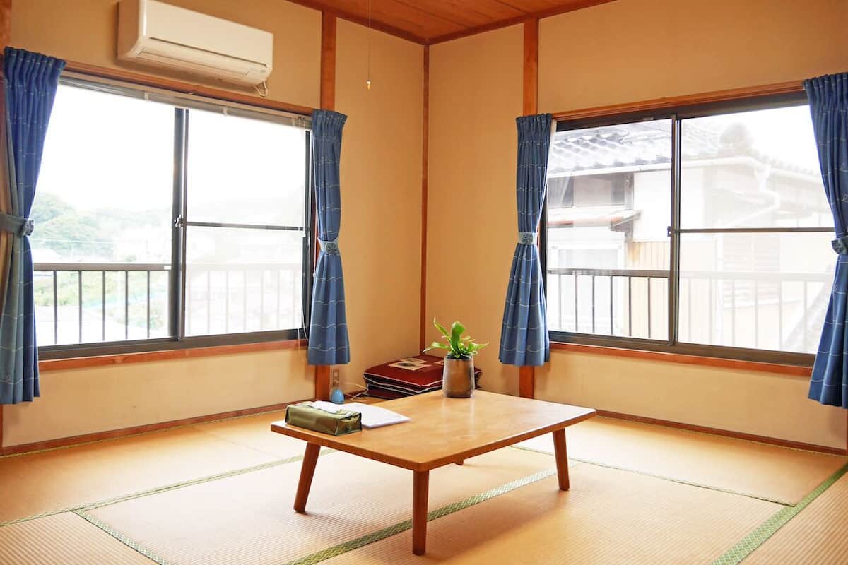 A traditional Japanese room with tatami flooring, a low wooden table, and a small plant.