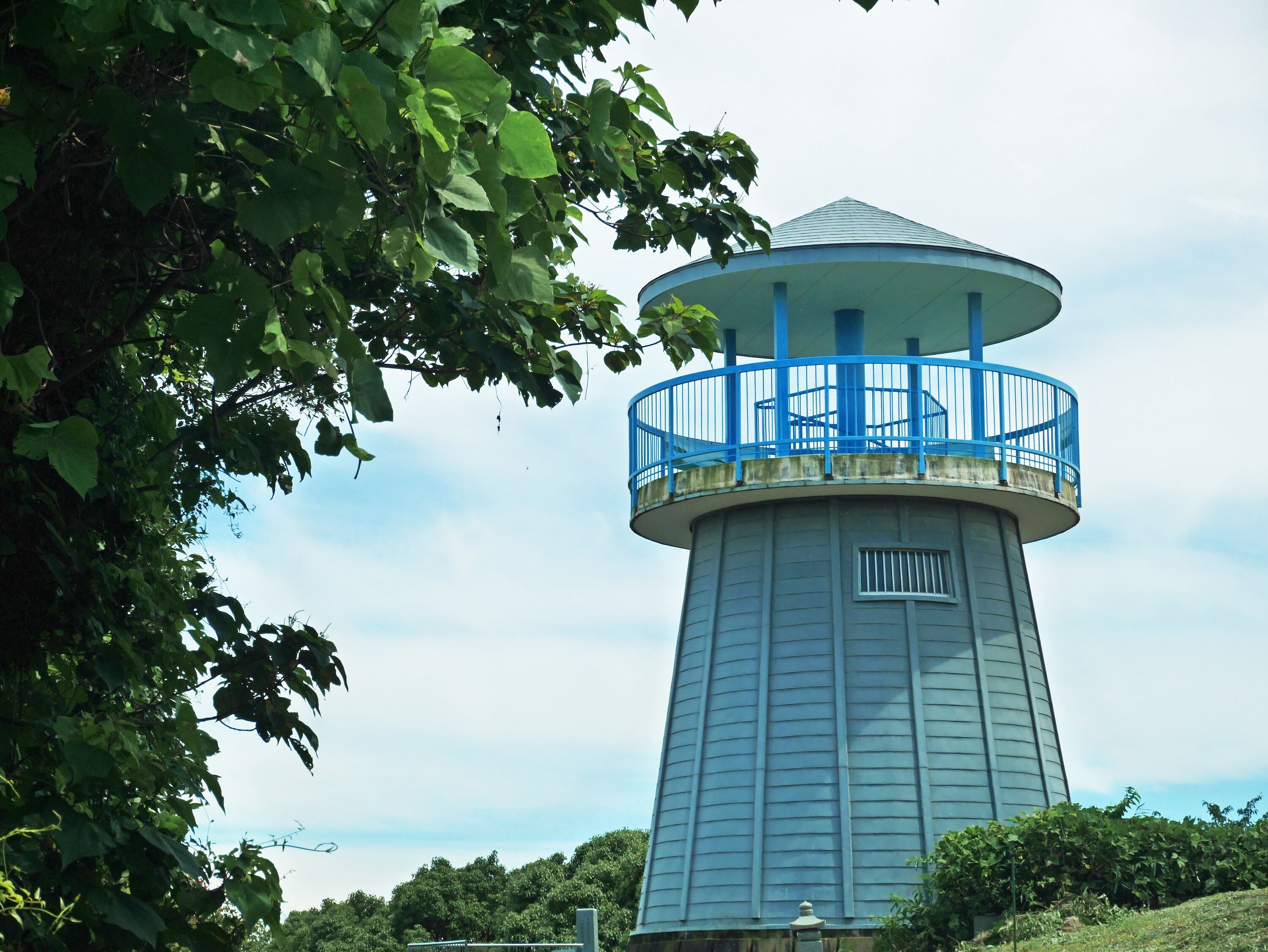 Una torre de agua cilíndrica con un balcón azul.