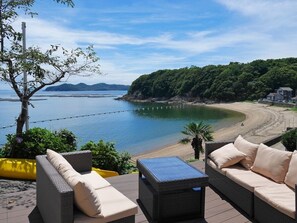 A seaside patio with wicker furniture and a view of the beach. - Pension Oyaji no Umi (Bizen)