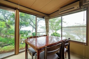 Un comedor con mesa y sillas de madera, ventanas amplias con cortinas y un equipo de aire acondicionado.