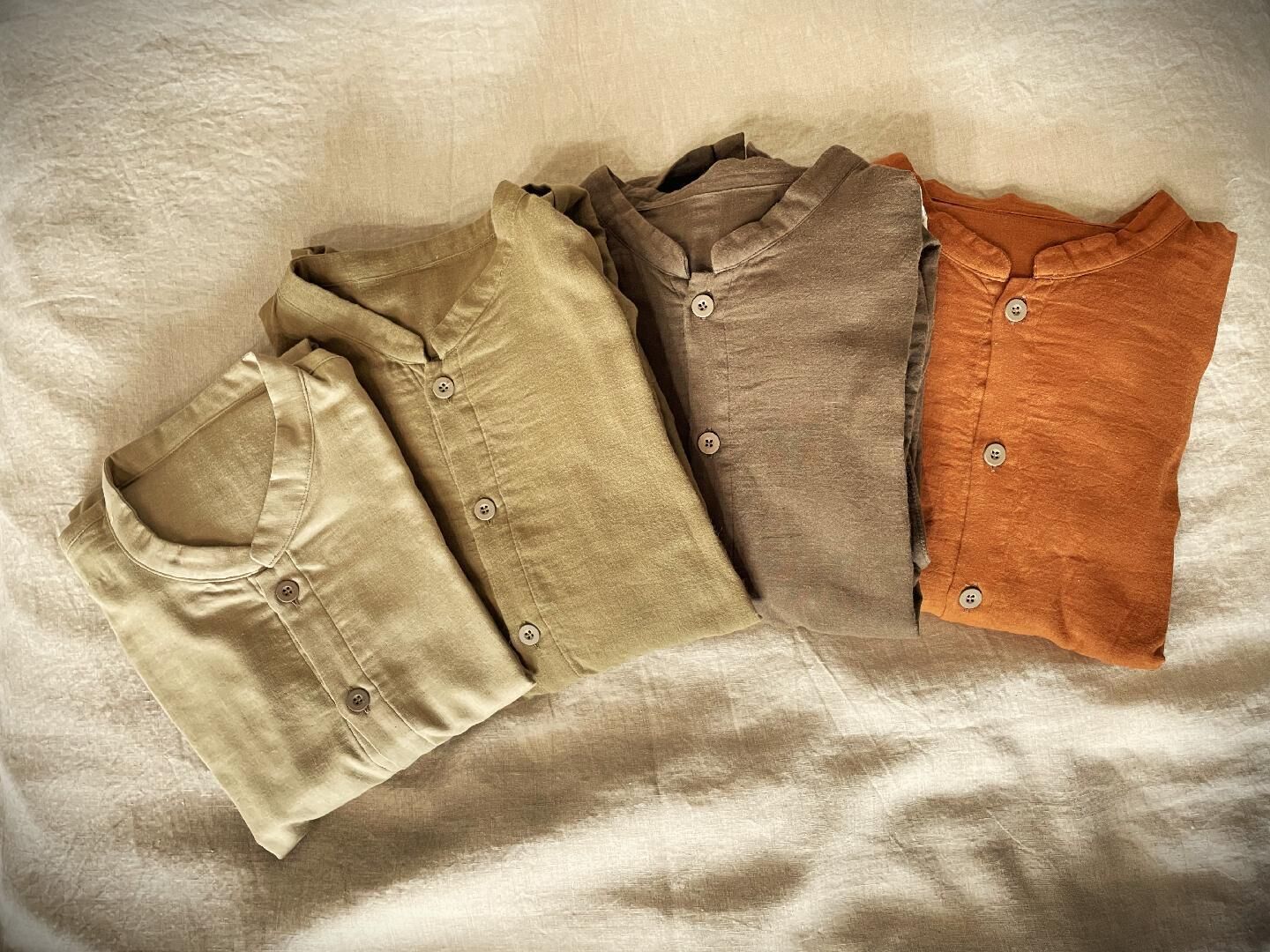 Four shirts laid out on a textured surface.
