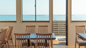 A room with a view of the sea, wooden chairs, a table, and a door leading outside. - Lorchidee Awajishima (Awaji)