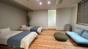 A hotel room with two beds, a sofa, a potted plant, and a view of the hallway. - Lorchidee Awajishima (Awaji)