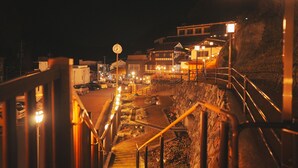 A nighttime view of a town with a clock tower, a staircase leading down, and buildings with traditional architecture. - Showcase Hotel Kasane (Gotsu)