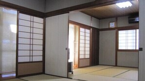 Una habitación japonesa tradicional con suelo de tatami, paneles shoji y techo de madera.