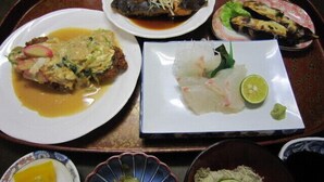 Una bandeja con diferentes platos, incluyendo pescado, ensalada y una rodaja de lima.