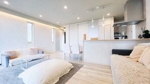 Uma sala de estar moderna com sofá, mesa de centro e área de jantar com cadeiras.