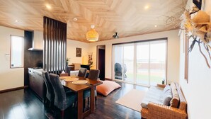 Uma sala de estar moderna com uma mesa de jantar de madeira, assentos confortáveis, uma janela grande com vista e uma lareira acolhedora.